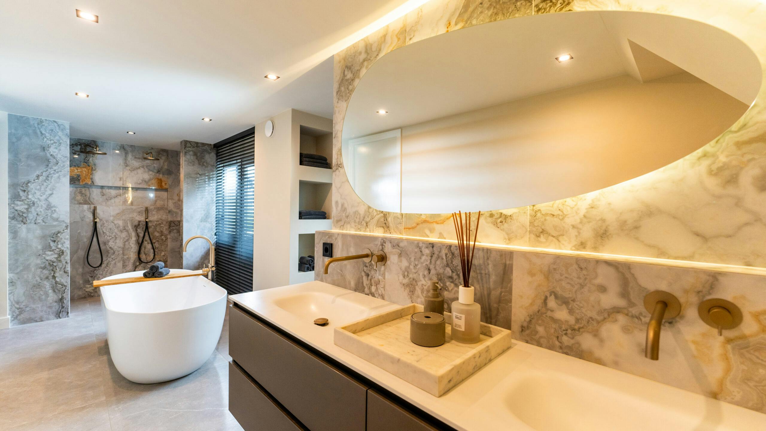 Badkamer met een luxe bruine wastafel een grote vierkante spiegel vanaf de zijkant met het licht aan